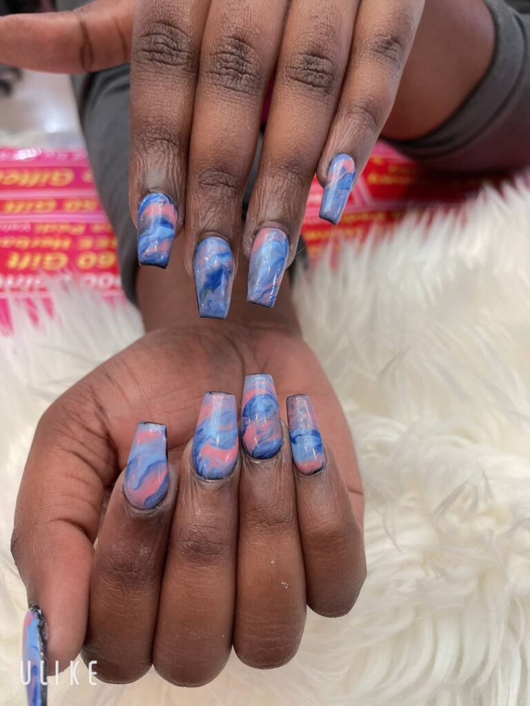 Abstract marbled blue nail art, resembling a fluid watercolor painting, at The Grand Nails of America in Houston.