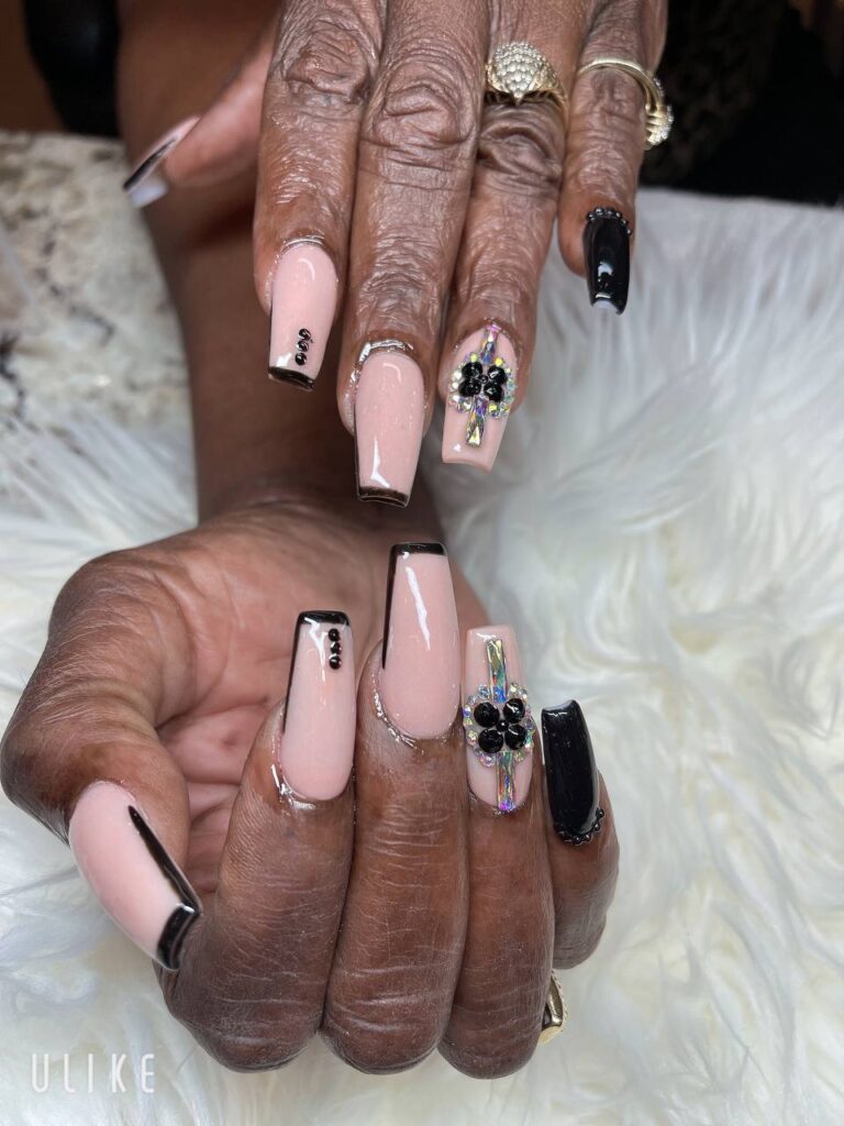 Elegant nail art with pink and black polish, accented with intricate jewel embellishments at The Grand Nails of America in Houston
