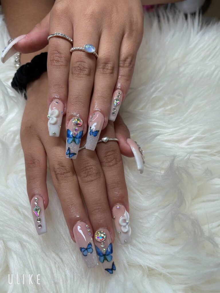 Elegant nail art with whimsical 3D butterflies and pearl accents from The Grand Nails of America in Houston.