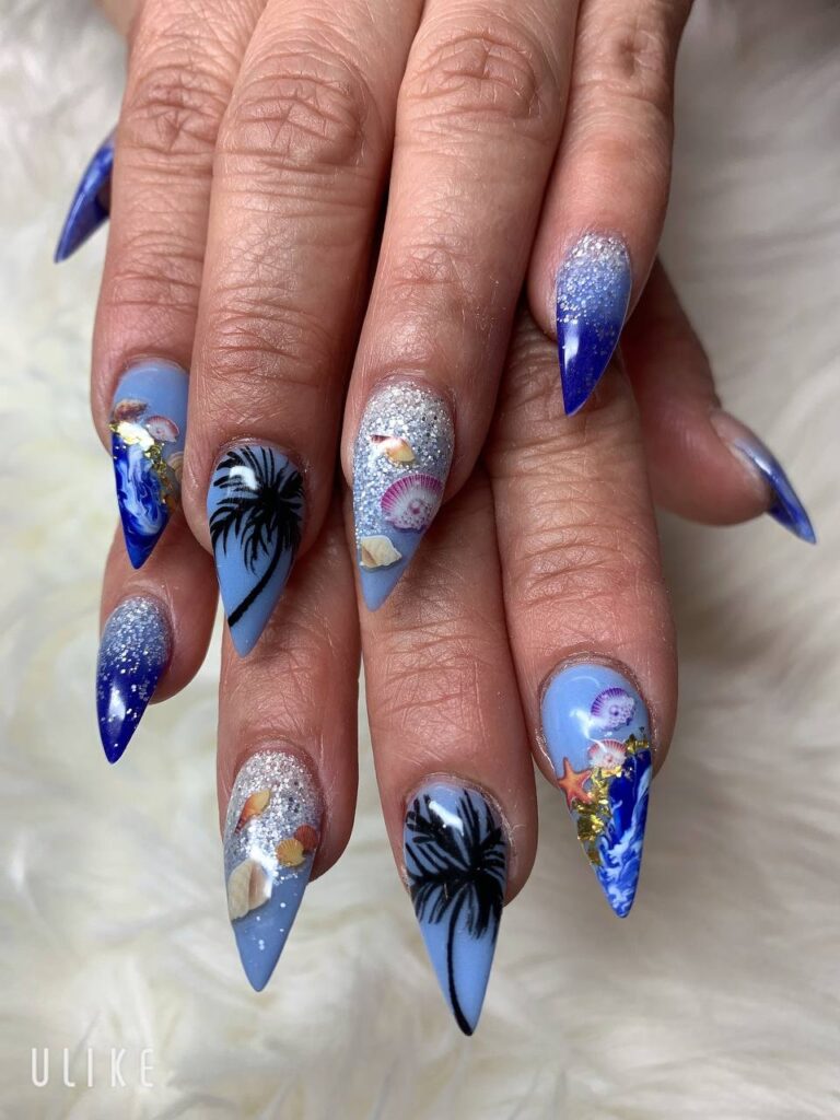 Ocean-inspired stiletto nail art with vivid blue tones and intricate beach designs at The Grand Nails of America in Houston