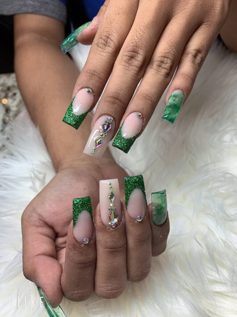 Exquisite French tip nails with a vibrant green glitter base and elegant rhinestone accents from The Grand Nails of America in Houston