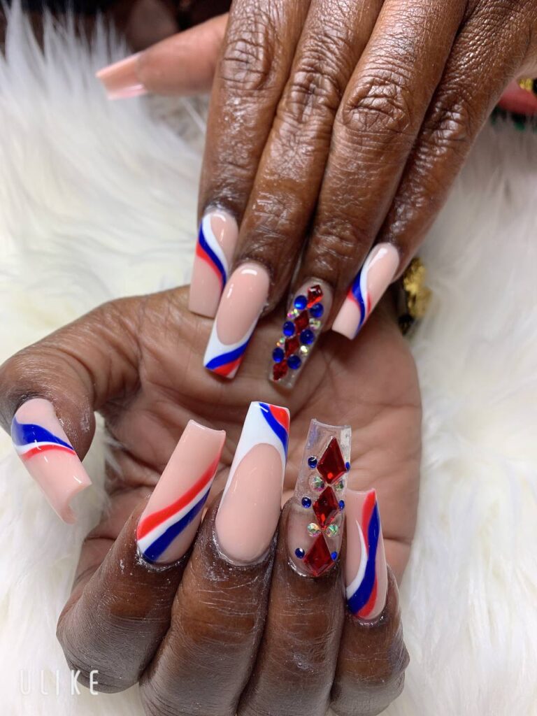 Fashionable coffin nails featuring a bold red, white, and blue design with sparkling rhinestone accents, showcasing the creative talent at The Grand Nails of America in Houston, Texas