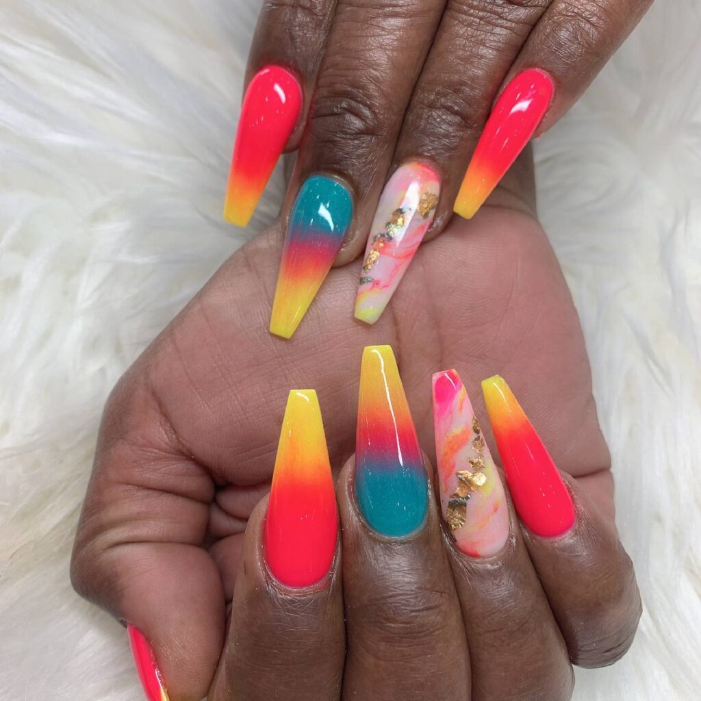 Vivid long coffin nails with a radiant sunset ombre effect and embellished accent nails, reflecting the vibrant artistry of The Grand Nails of America in Houston, Texas