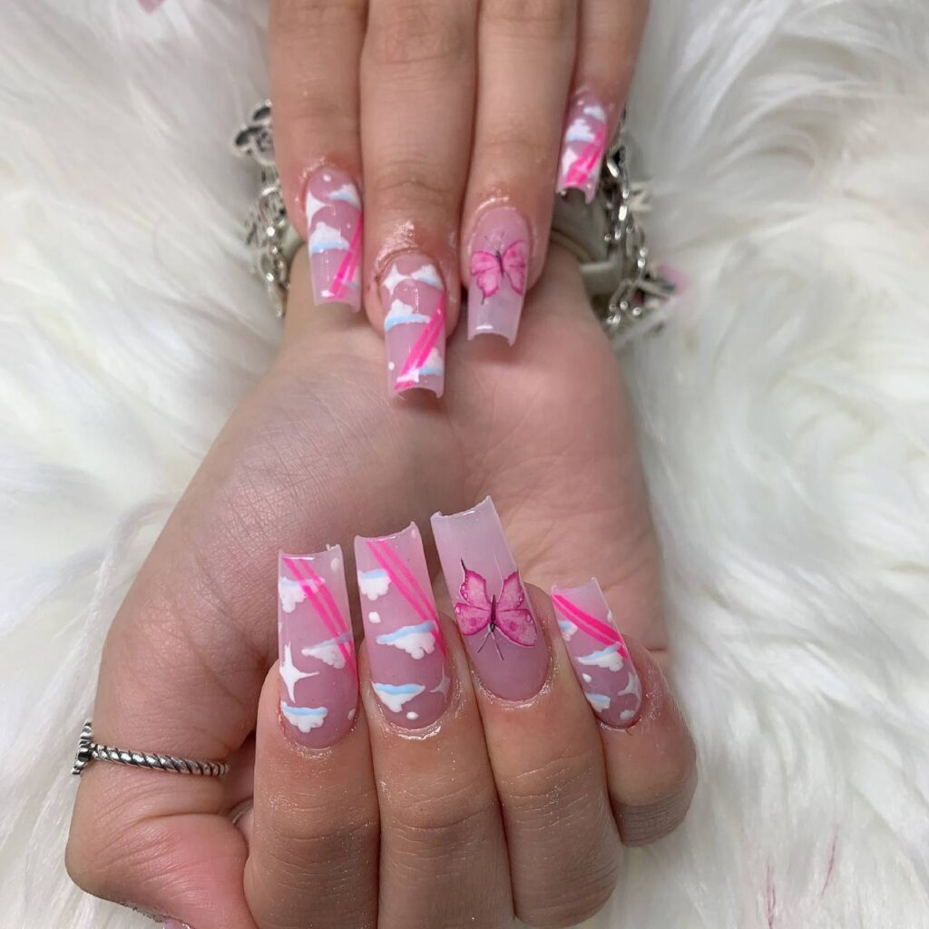 Chic long coffin nails with a transparent base and delicate pink butterfly wing accents, showcasing The Grand Nails of America's artistry in Houston, Texas.