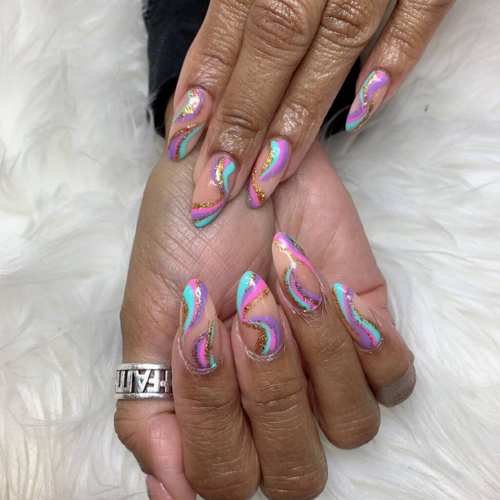 Graceful almond-shaped nails featuring a whimsical pastel swirl design with gold accents, crafted by The Grand Nails of America in Houston, Texas.
