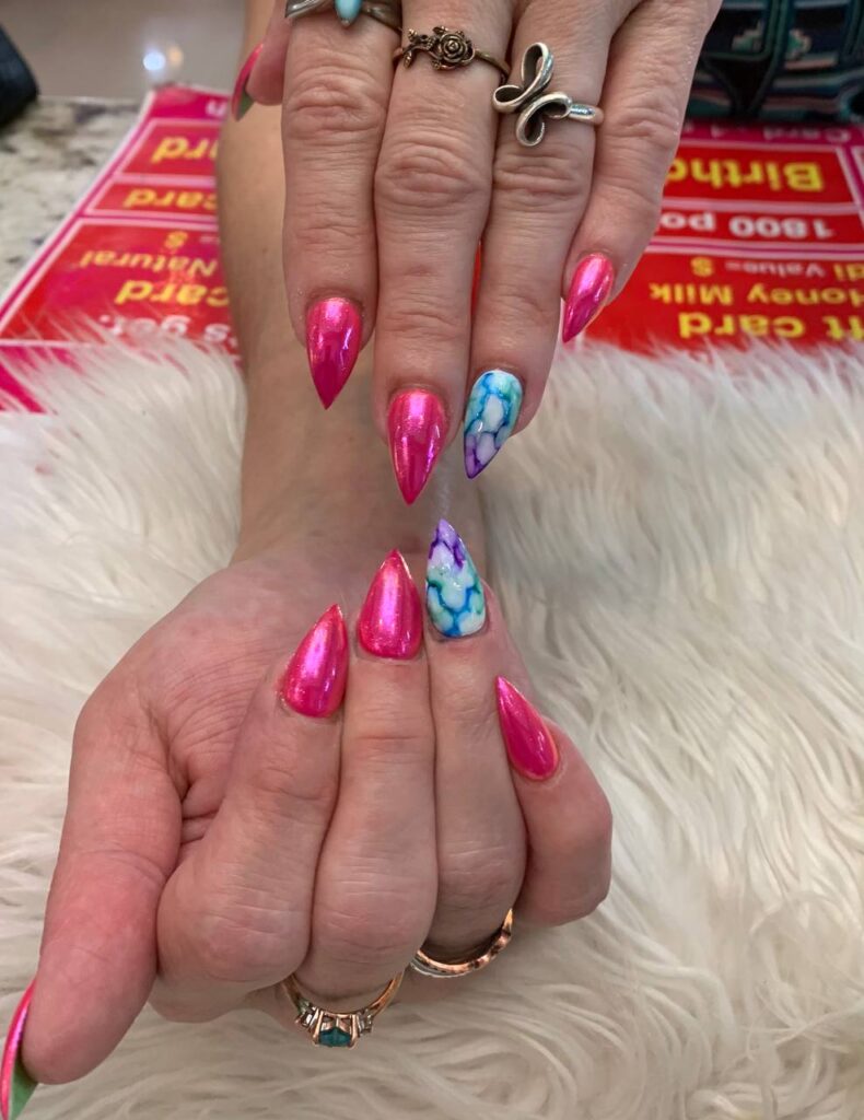 Vibrant pink stiletto nails interspersed with delicate marbled designs capture the artistic flair of The Grand Nails of America, Houston's premier nail salon