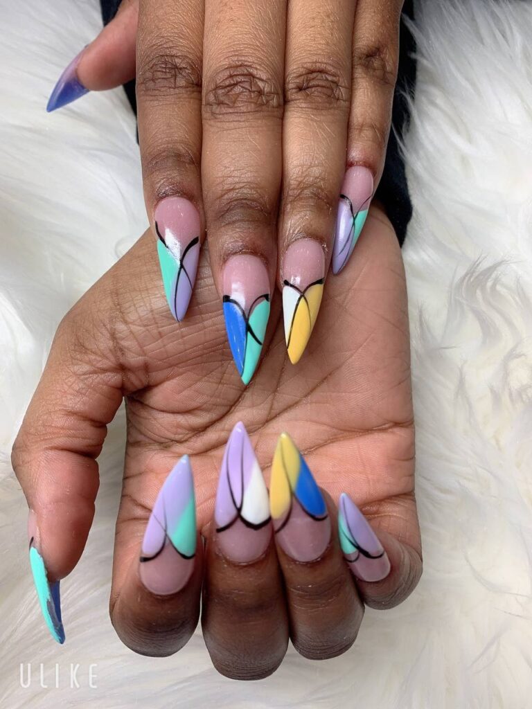 Expertly crafted stiletto nail art by The Grand Nails of America, featuring a creative geometric design in pastel tones, a signature style in Houston, Texas, presented on a plush white background.